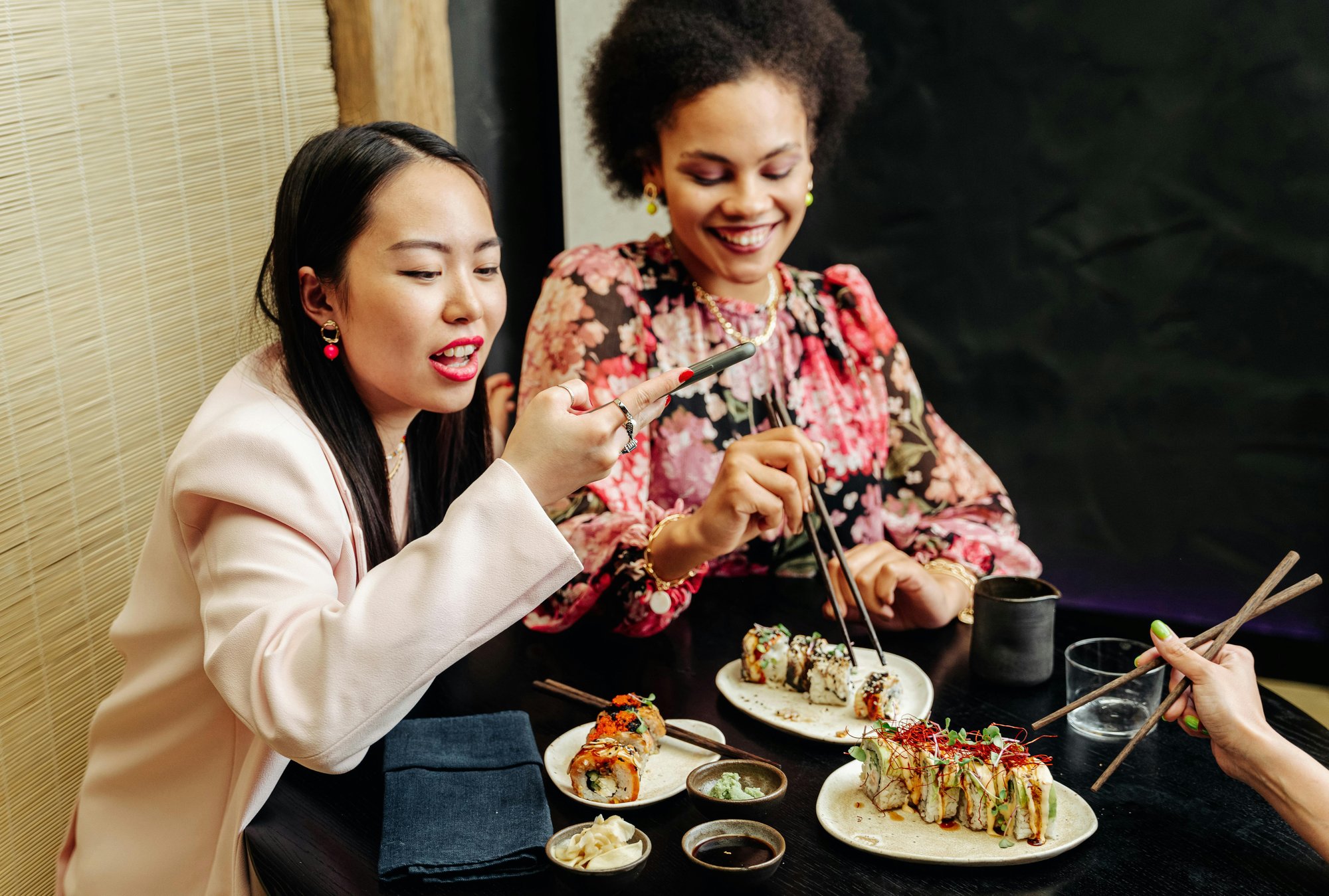 Une femme asiatique et une femme métisse à table en train de manger de la cuisine japonaise Une femme asiatique et une femme métisse à table en train de manger de la cuisine japonaise